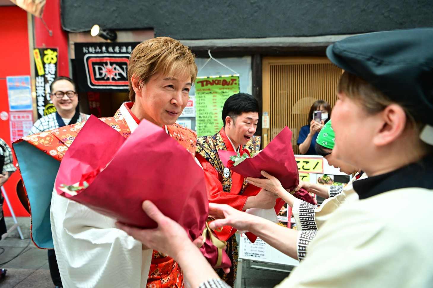 商店街の人たちに花をもらう吉田裕とアキ。
