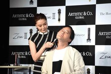 観月ありさ（左）に美顔器をあててもらうアインシュタイン稲田（右）。