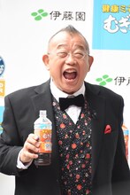 報道陣に向かって「健康ミネラルむぎ茶」を飲んで見せる笑福亭鶴瓶。