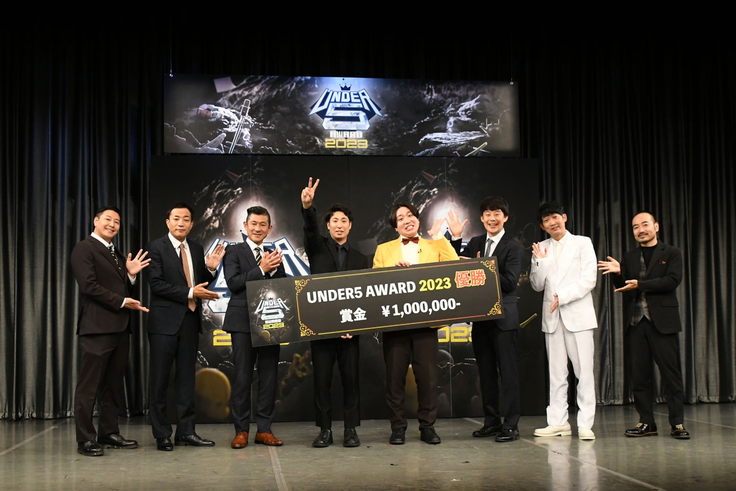 前回大会の様子。優勝した金魚番長（中央）と、審査を務めたチョコレートプラネット長田、ナイツ塙、笑い飯・哲夫、佐久間一行、NON STYLE石田、かもめんたる・う大（左から）。