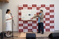 枕を頭に付けたまま司会者とトークするチョコレートプラネット長田。