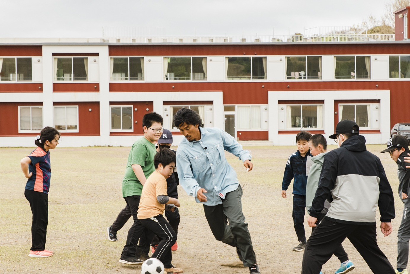 中澤佑二が礼文島で子供たちとサッカーをするワンシーン。(c)UHB