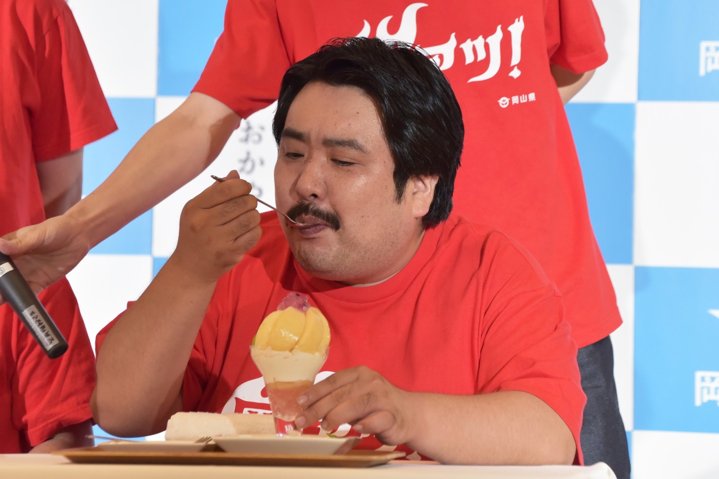 岡山グルメの試食をする空気階段・鈴木もぐら。
