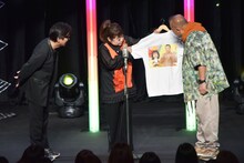 若き日の笑福亭鶴瓶と藤井フミヤがプリントされたTシャツの裏表で、若き日の鶴瓶と天童よしみがプリントされているのを紹介するワンシーン。