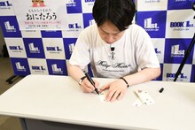 しおりにサインを入れる見取り図リリー。