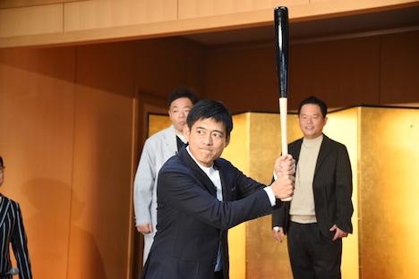 “ホームラン祈願バット”で構える博多華丸。