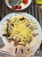 炒めたにんにく、ベーコンとチーズを生地にかける。