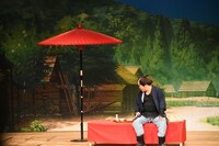 旅の序盤、三色団子を食べながら日本酒を飲む弥七（マユリカ中谷）。