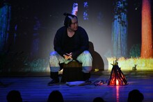 山の中で焚き火をする弥七（マユリカ中谷）。