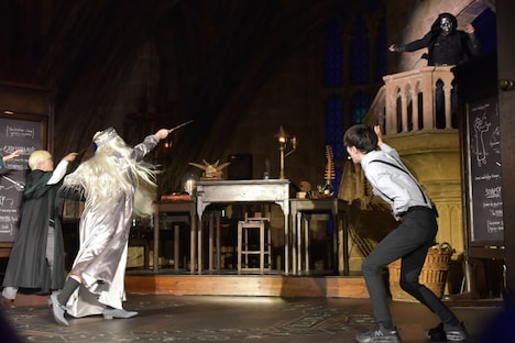 悪役・デスイーター（右後方）を、杖を用いて退治する霜降り明星せいや（手前左）。