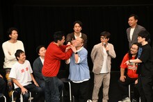 芸人詐称を疑うサルゴリラ赤羽の口を大きな手で覆って真空のような状態にしてみせる、や団・ロングサイズ伊藤。