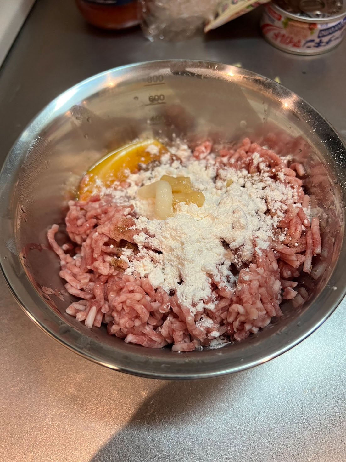 ボウルにひき肉、卵黄、にんにく、しょうがを入れ、炒めた玉ねぎを加えて混ぜる。