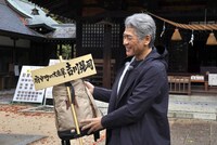 看板を手渡され思わず笑顔になる吉川晃司。(c) テレビ新広島