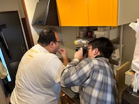 味見する大鶴肥満さんを撮影する檜原さん。