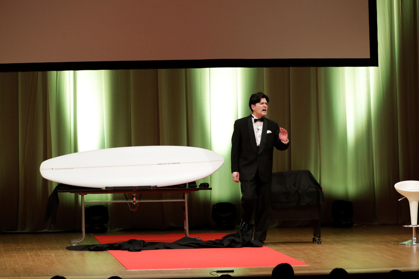 中谷からサーフボードをもらうも、「いらんいらん」と拒否するマユリカ阪本。（写真提供：吉本興業）