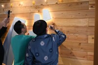 「バ」の看板にサインを入れるバナナマン。