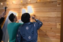 「バ」の看板にサインを入れるバナナマン。