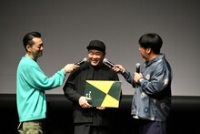 スケッチブックをめくるオークラのマイクフォローをするバナナマンの2人。