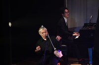 アサラトを演奏するのに頭から垂れている紐が邪魔そうな塚本。