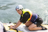 水面から引き上げられる久地々ディレクター（ジャルジャル後藤）。(c)Daichi Mononobe／Red Bull Flight Day
