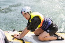 水面から引き上げられる久地々ディレクター（ジャルジャル後藤）。(c)Daichi Mononobe／Red Bull Flight Day