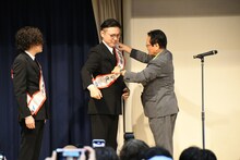 井澤邦夫市長に大使のたすきをかけてもらうガクテンソク奥田。