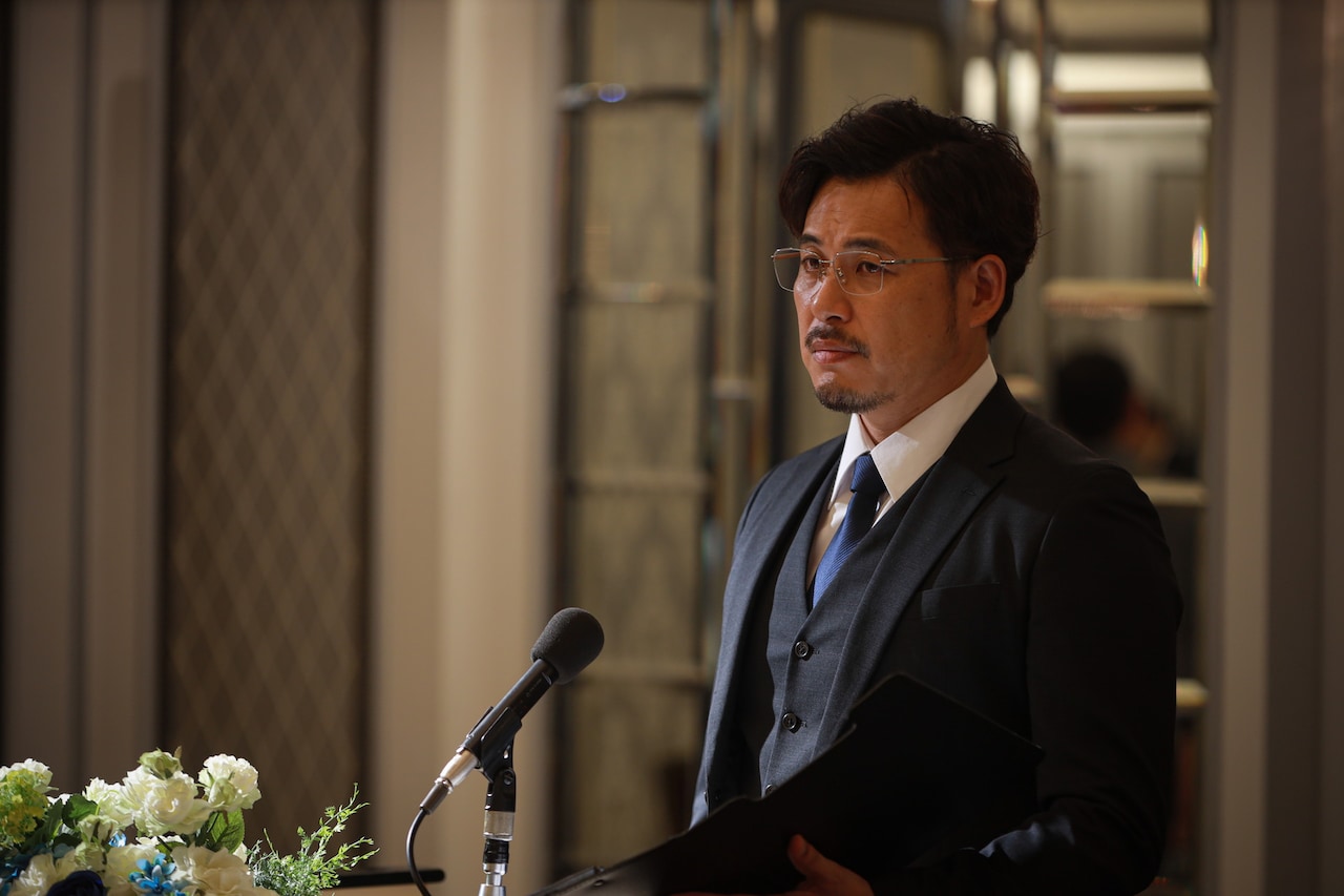 ドラマ「スカイキャッスル」で“秘密の教育セミナー”の司会役を演じるアルコ＆ピース平子。(c)テレビ朝日