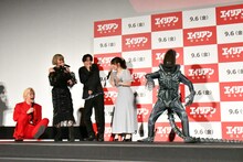 「エイリアン：ロムルス」公開直前イベントで「エイリアン」最終形態に扮した研ナオコ（右端）の登場に腰を抜かしてみせるメイプル超合金カズレーザー（左端）。(c)2024 20th Century Studios. All Rights Reserved.