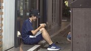 牛丼店の軒先で、牛丼を食べている男性。テイクアウトして消費税分を節約している。