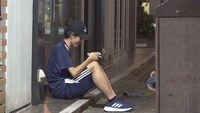 牛丼店の軒先で、牛丼を食べている男性。テイクアウトして消費税分を節約している。