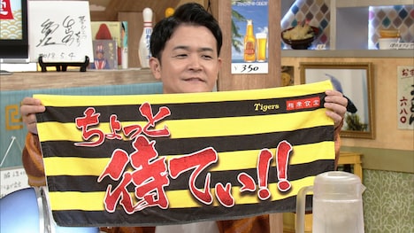 「相席食堂」と阪神タイガースのコラボフェイスタオルを掲げる千鳥ノブ
