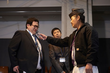 「怪獣ヤロウ！」より、マイクを押し付けられる山田（春とヒコーキ・ぐんぴぃ）