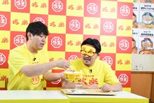 伊藤に「日清ラ王 兆楽監修広東麺」を食べさせてやるオズワルド畠中（左）