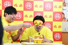 伊藤に「日清ラ王 兆楽監修広東麺」のスープを口に運んでやるオズワルド畠中（左）