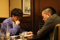 喫茶店でネタ作りを行うエバース佐々木と、見守る町田