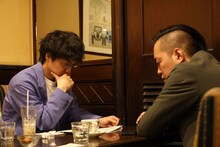 喫茶店でネタ作りを行うエバース佐々木と、見守る町田