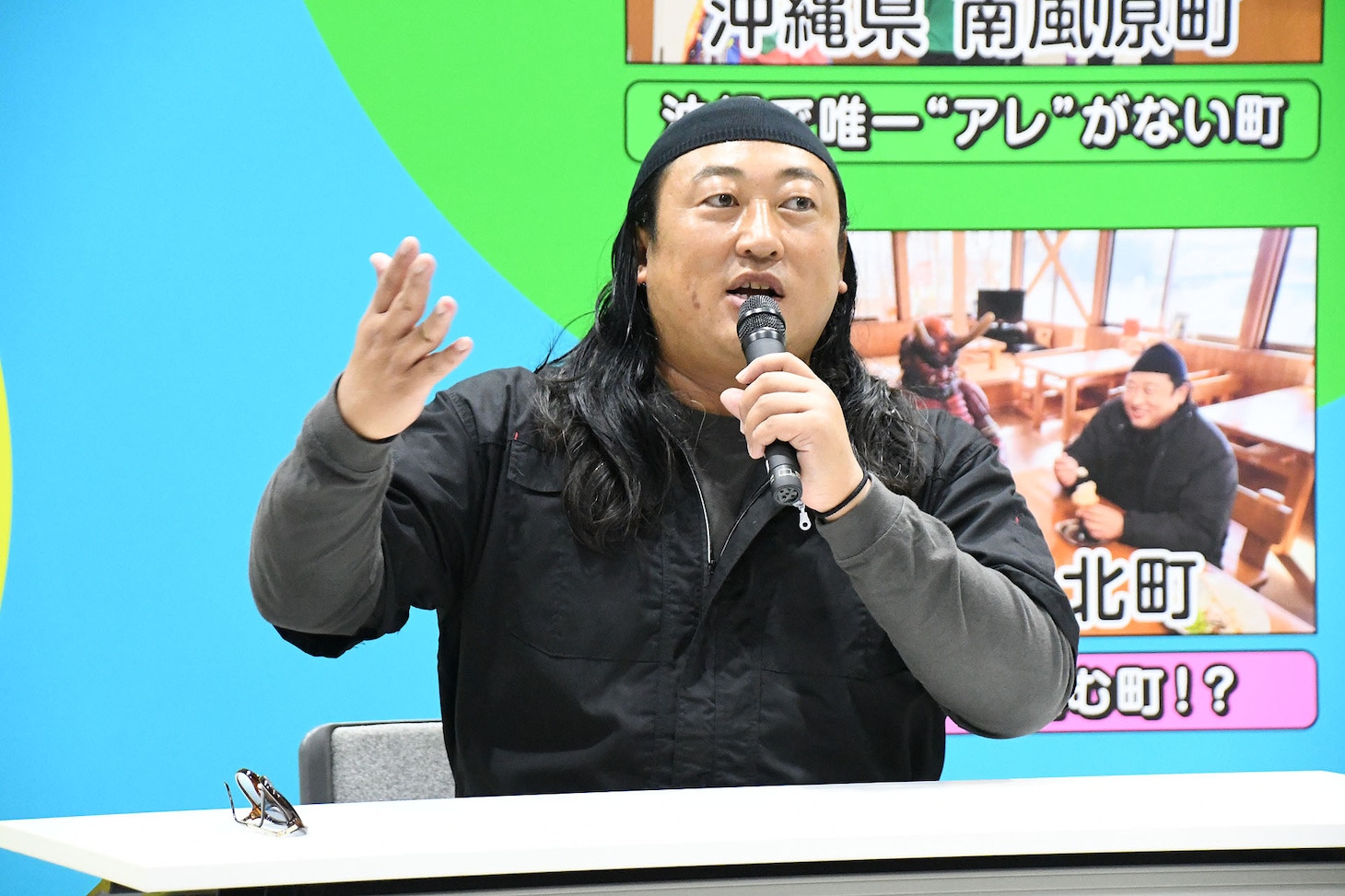 「緊急！町民オーディション」の見どころを説明するロバート秋山