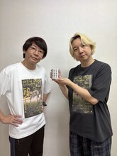 「祝！結成20周年 記念湯呑み」を持つ三四郎