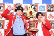 フォトセッション中のロングコートダディ。トロフィーが重く、兎（右）の腕に限界が近づく