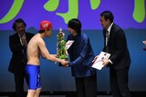同じ出場者だったはずの本多スイミングスクールからトロフィーを受け取るヤッホイ
