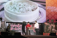 野田の母が手作りした“シウマイ”をステージ上で試食する場面