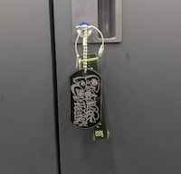 「ヤマゲンデザイン『Prank Permit』BLACKタグ」。一緒に付いているのはシティホテル3号室のグッズのホテルキー