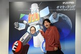 股間戦士エムズーンの股間部分の顔はめパネルに顔をはめた春とヒコーキ・ぐんぴぃと、その横に立つ土岡
