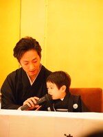 中村七之助（左）に介添えされながらマイクで話す波野哲之。