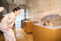 一葉の家の模型を見つめる永作博美。