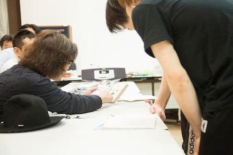 原作マンガを見せつつ説明する西田大輔。