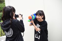 水鉄砲で遊ぶ真山りか（右）を撮影する中山カメラマン（左）。