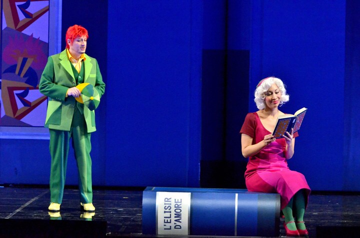 大きな本や小型飛行機など遊び心に富んだ演出も、新国立劇場「愛の妙薬」