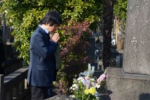 三遊亭円朝の墓に手を合わせる演出家の鵜山仁。