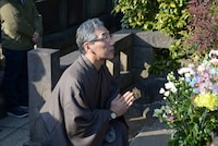 三遊亭円朝の墓に手を合わせる三遊亭円朝役の大原康弘。